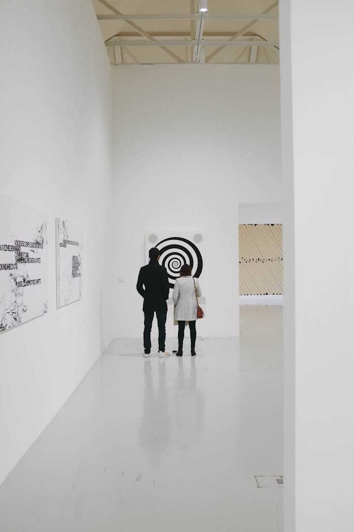Two visitors admire contemporary artwork in a minimalist gallery setting.